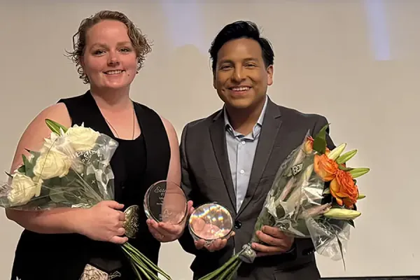 Two professionals holding bouquets and award glasses at The Arc Illinois 'Together, We Rise' Awards Reception event, with the event banner visible behind them.