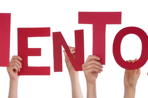 Hands holding up red letters spelling 'MENTOR'.