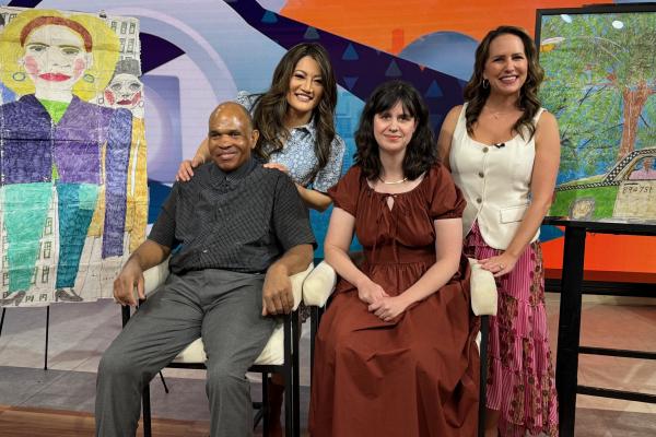 A group of individuals poses behind the scenes at a news studio