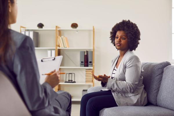 A woman sits on a couch during a therapy session