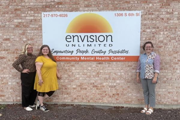 A group of Envision Staff members stands in front of signage for the Springfield Mental Health Center