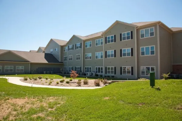 A housing complex is pictured with a clear blue sky and a grassy landscape