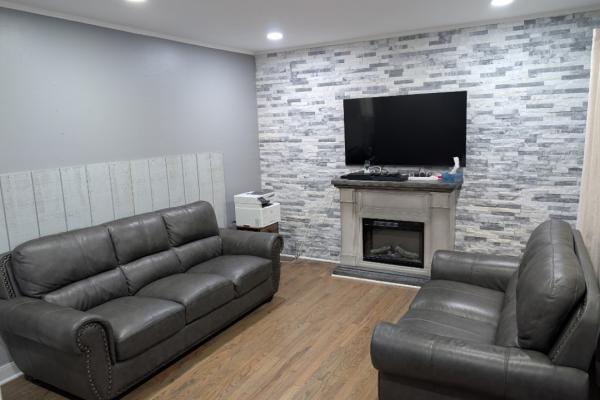 A brightly lit living room is pictured with two couches and a television