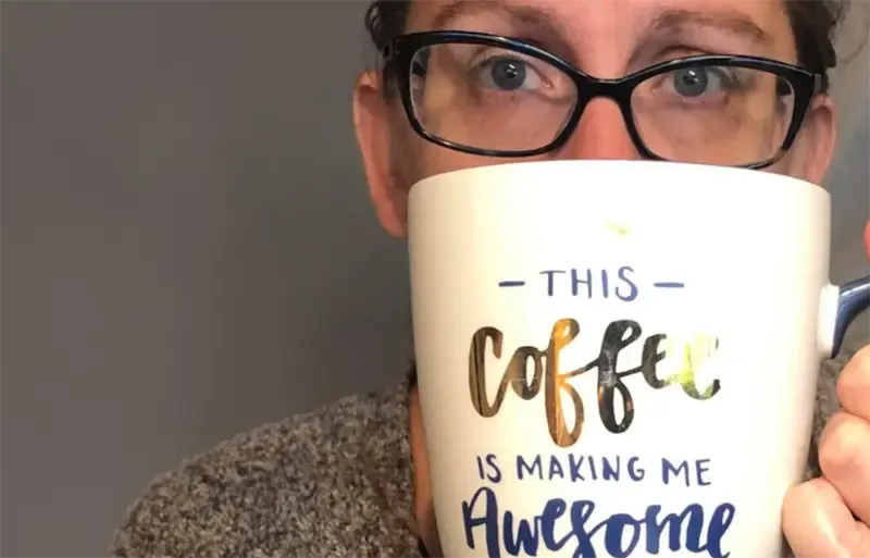 Person holding a large white coffee mug with motivational text - 'This coffee is making me awesome'