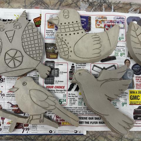 A collection of pottery in the shape of birds is displayed