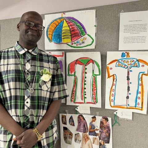 A person standing next to a board with drawings.