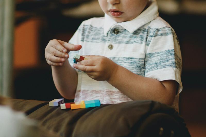 A child is pictured playing with a set of colorful blocks