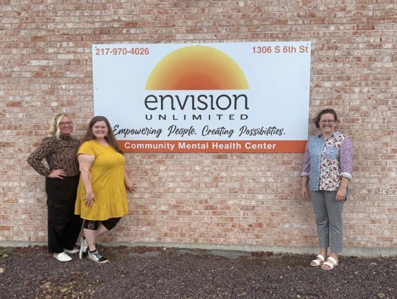 A group of Envision Staff members stands in front of signage for the Springfield Mental Health Center