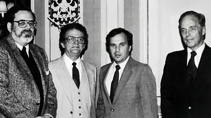 Four men in suits, standing indoors