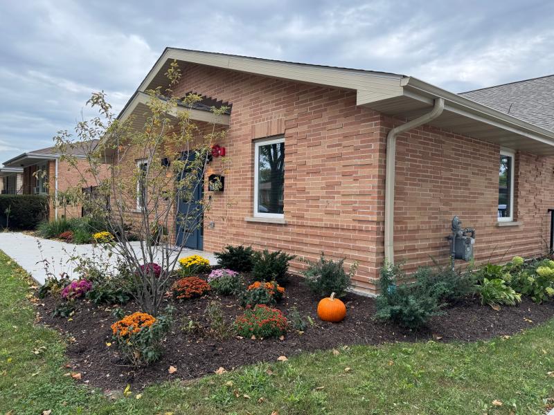 A cheerful home is pictured with a landscaped gardens