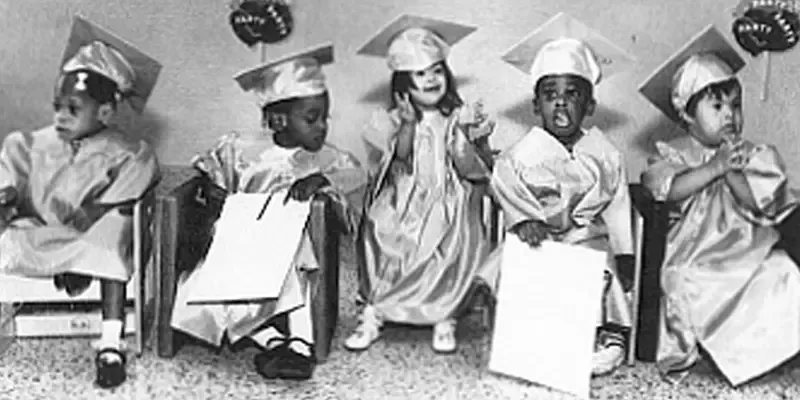Children in graduation caps and gowns seated