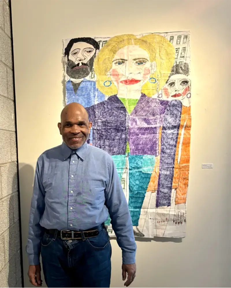 A man standing in front of a colorful, abstract artwork featuring three figures.