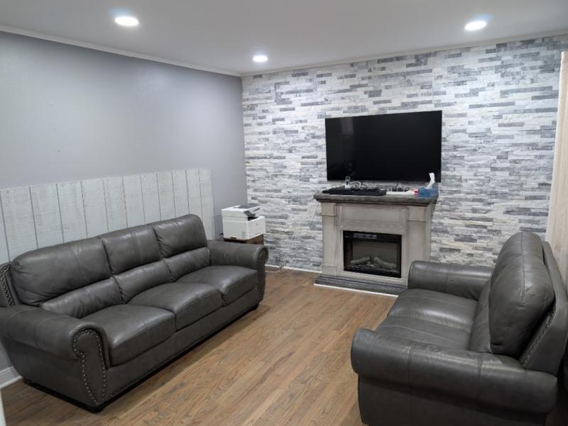 A brightly lit living room is pictured with two couches and a television